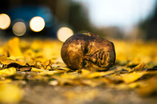 A doll head lies on a bed of leaves in fall