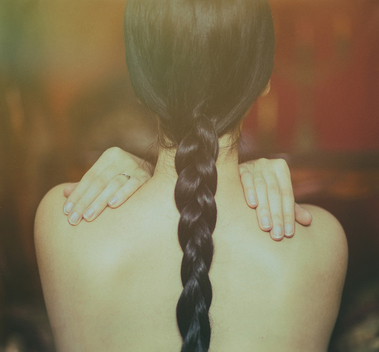 back view of young woman with long black plait, bare back,