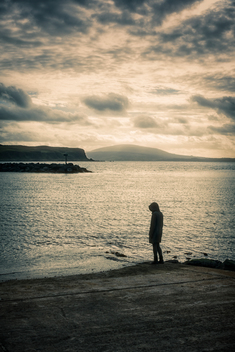 Lone Hooded Pensive Woman by the Sea in Rathlin Island, Northern Ireland, United Kingdom